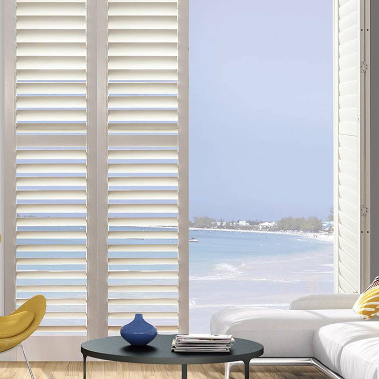 Partially opened plantation shutter with a beautiful beach view